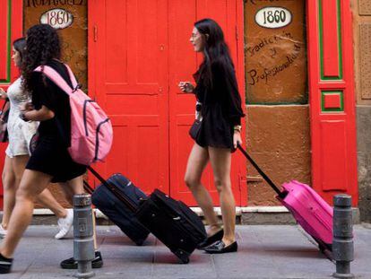 Tres jóvenes turistas llevan sus maletas por la calle de las Maldonadas de Madrid.