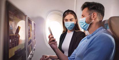 Dos viajeros consultan el teléfono móvil en un vuelo de Etihad.