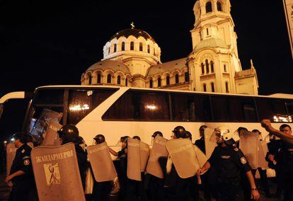 Agentes de policía protegen el autobús que intentaba salir del Parlamento de Sofía, 23 de julio de 2013. Los manifestantes, críticos con las decisiones adoptadas por el Gobierno de Plamen Oresharski, han arrojado botellas de plástico y otros objetos contra el autobús a bordo del cual viajaban los diputados, que intentaban abandonar el Parlamento tras debatir medidas presupuestarias.