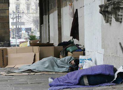 Varias personas sin hogar protegiéndose del frío con cartones y mantas  en pleno centro de Bilbao.