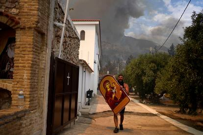 Un hombre transporta a la virgen para evitar que se queme, en un monasterio de Acarnas, este miércoles. 