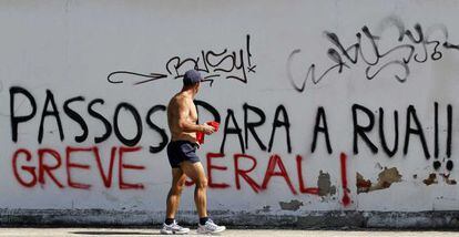 Un hombre pasa ante un graffiti que reza: "Passos a la calle, huelga general".