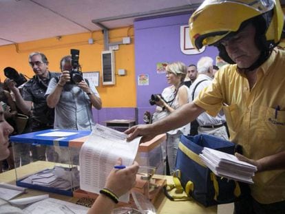 Un cartero entrega el voto por correo en una mesa de un colegio electoral de L'Hospitalet de Llobregat (Barcelona), en las elecciones generales de 2016. 
