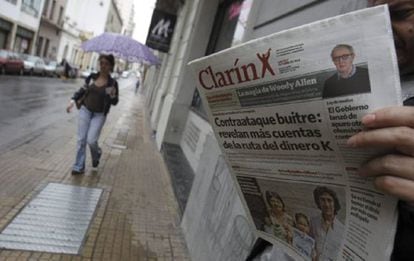 Un hombre lee un ejemplar del diario Clarín en una calle de Buenos Aires.