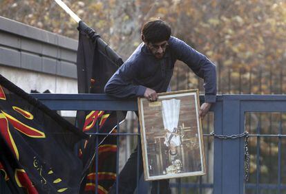 Un manifestante saca del interior de la Embajada británica en Teherán un retrato de la la reina Isabel II.
