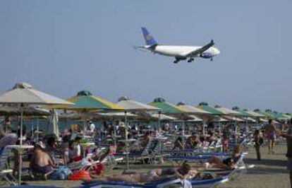 Un avión de una aerolínea chipriota sobrevuela una playa llena de turistas próxima al aeropuerto en Larnaca (Chipre). EFE/Archivo