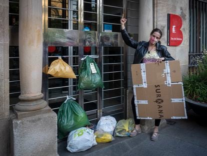 Una vecina coloca bolsas de basura en la puerta de la sede del distrito de Sant Andreu