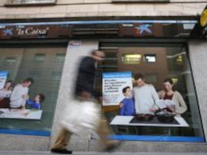 Un hombre pasa delante de una oficina de La Caixa en Madrid. 