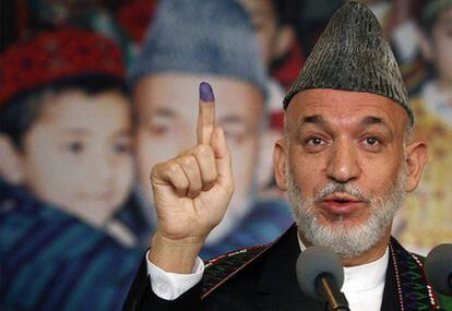 El presidente Karzai enseña su dedo marcado tras votar en un centro electoral de Kabul