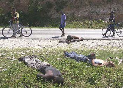 Tres haitianos observan los cadáveres de hombres asesinados en Petit Goave, al sur de Puerto Príncipe.