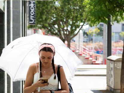Una mujer pasea protegida por un paraguas en Lleida.