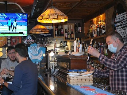 Víctor Rey sirve unas cervezas en su bar, El rincón del Greco. De fondo, un informativo de LaLiga Santander. 