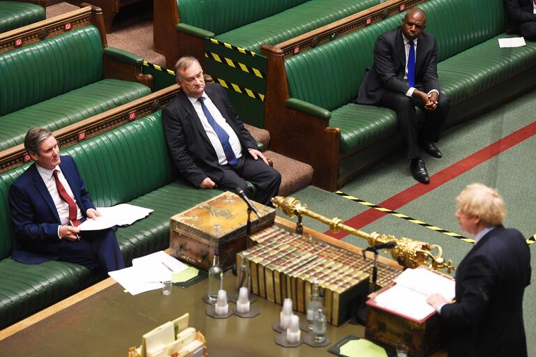 Keir Starmer escucha sentado este miércoles la réplica de Boris Johson en una Cámara de los Comunes casi vacía.