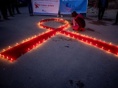 Mujeres y niños del orfanato de rehabilitación para enfermos de sida 'Maiti Nepal', encienden varias velas de manera que forman un lazo rojo en Katmandú (Nepal).