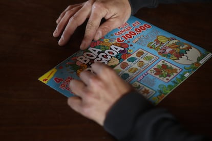 Un hombre rasca en un cartón de lotería portugués. 