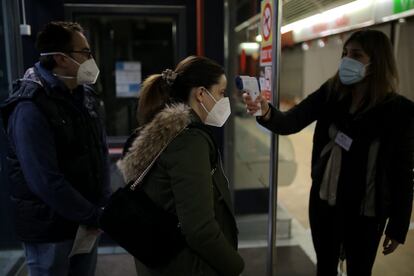 Una mujer toma la temperatura a la entrada del mercado de la Sagrada Familia, Barcelona. La Generalitat ha explicado que los ciudadanos podrán descargarse una aplicación para ver la afluencia de gente en los colegios.