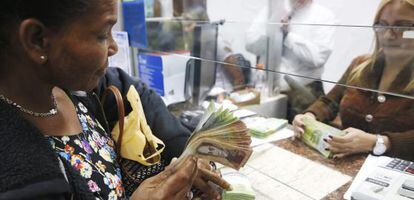 Una mujer cambia bol&iacute;vares por d&oacute;lares en una casa de moneda en Caracas, el pasado febrero. 