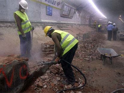 Dos obreros inmigrantes trabajan con un martillo neumático en las obras de la estación de metro de Callao.