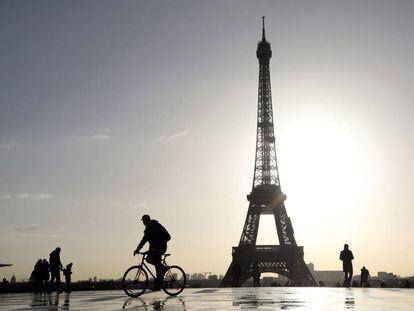Un ciclista y varios paseantes, frente a la torre Eiffel de París.