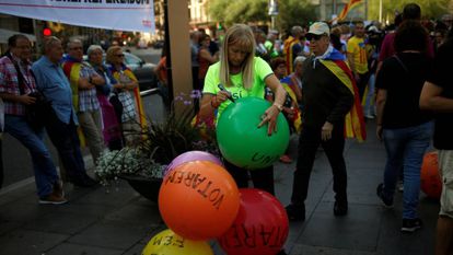 Una mujer escribe consignas a favor del referéndum del 1 de octubre en Cataluña en globos de colores en una concentración en Barcelona.