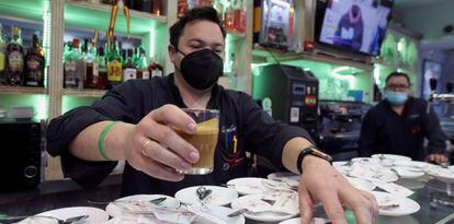 Una camarero poniendo un café en la barra de un bar.