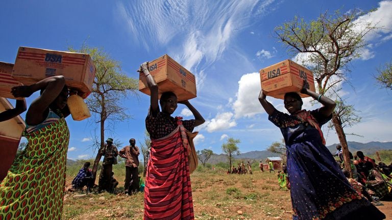 Mujeres de la tribu Dadinga llevan cajas de aceite durante la distribución de alimentos por el Programa Mundial de Alimentos.
