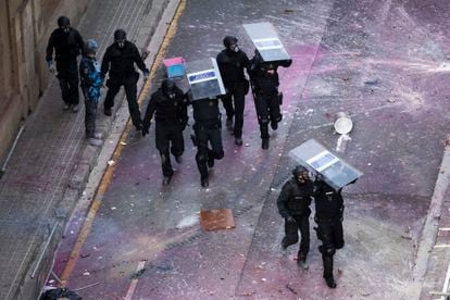 Un grupo de Mossos se protegen del lanzamiento de pintura mientras se acercan a uno de los edificios okupados. 