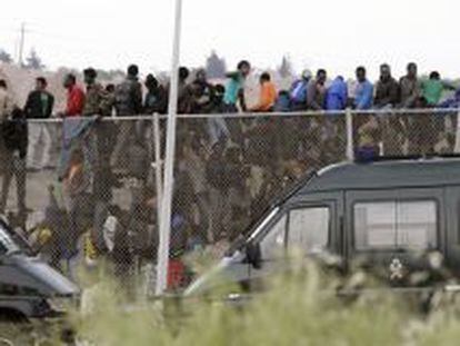 Inmigrantes subsaharianos que permanec&iacute;an encaramados a la valla de Melilla, tras protagonizar un intento de entrada masivo a la ciudad.