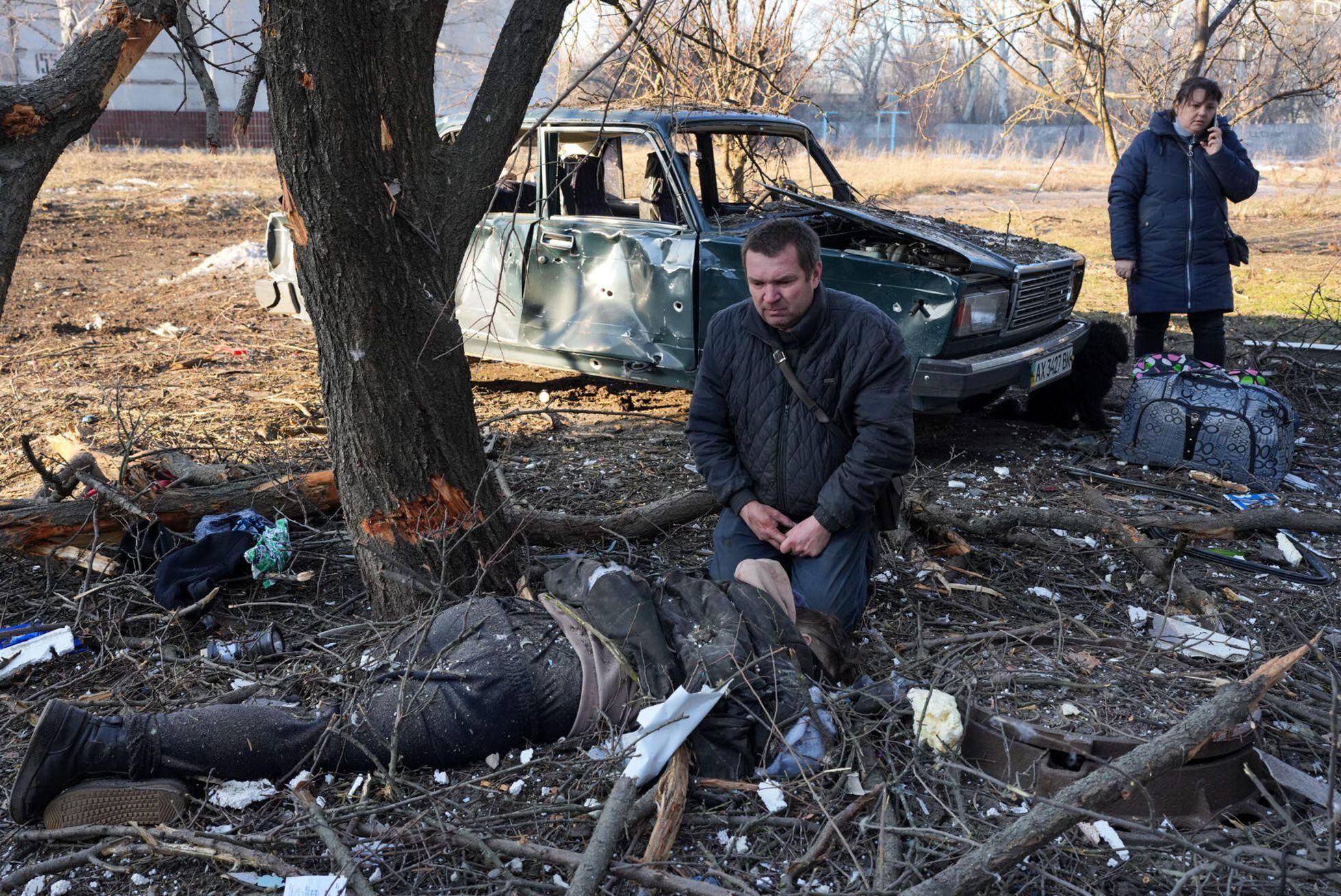 Un hombre arrodillado ante el cuerpo de una víctima de un bombardeo contra una zona residencial de Járkov, el 24 de febrero. 