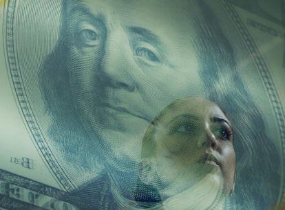 El retrato de Benjamin Franklin en un billete de 100 dólares se funde con el de una mujer en una estación de cambio de moneda en Singapur.