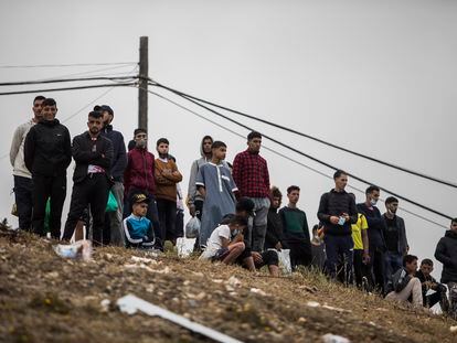Decenas de marroquíes aguardan tras haber sorteado el espigón que limita la frontera de Marruecos con España en Ceuta.