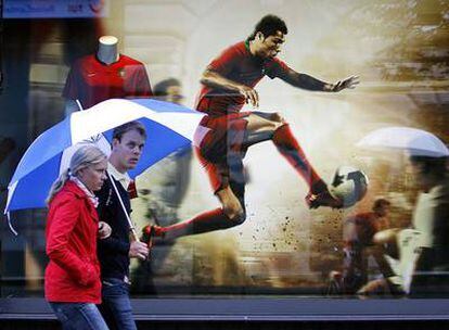 Dos espectadores pasan por delante de un cartel de Cristiano Ronaldo durante la pasada Eurocopa.