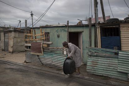 Una mujer arroja agua usada en un asentamiento informal cerca de Ciudad del Cabo el pasado 2 de febrero. Alrededor de un cuarto de la población de Ciudad del Cabo vive en este tipo de asentamientos, donde obtienen agua de grifos comunales en lugar de individuales en el hogar, como sucede en los barrios más ricos.