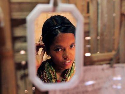 Nilima, una niña de Bangladesh de 14 años, reflejada en el espejo de su casa.