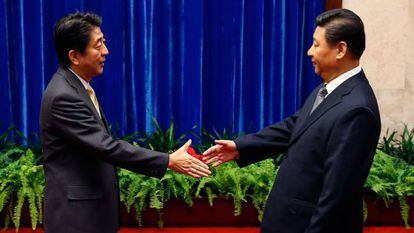 Abe (izq), primer ministro japonés, saluda a Jinping, su homólogo chino.