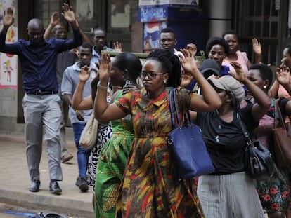 Un grupo de ugandeses levanta las manos durante la persecución policial de manifestantes pro Bobi Wine, este lunes en Kampala. 