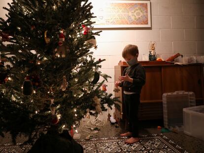 Un niño con mascarilla decora un árbol de Navidad en Nueva York.