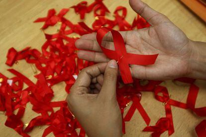 Una joven prepara lazos rojos en una campaña para la prevención del sida.