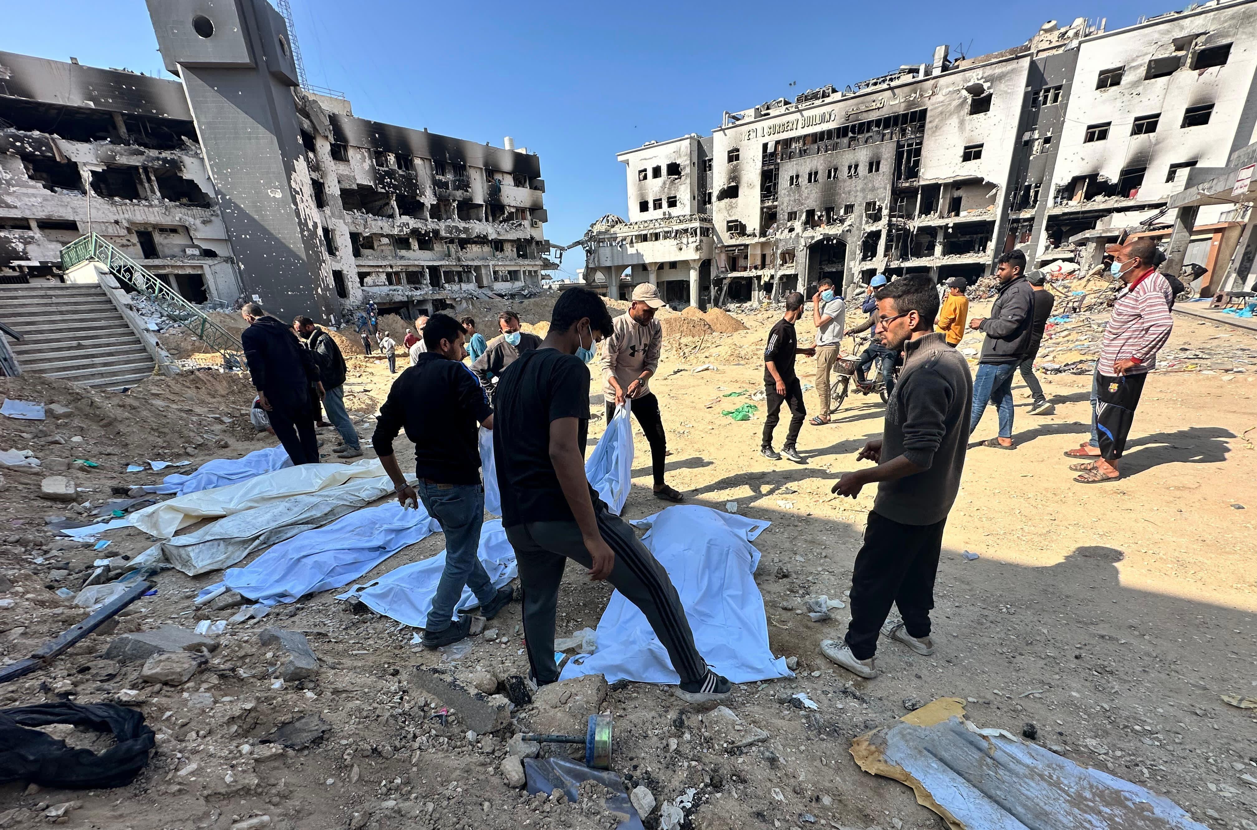 Varios palestinos retiran cadáveres de una fosa común hallada en el patio del hospital Al Shifa, en la ciudad de Gaza, Gaza, el 16 de abril de 2024