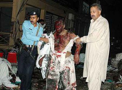 Un herido en el atentado suicida de ayer en Islamabad recibe ayuda para alejarse del lugar de la explosión.