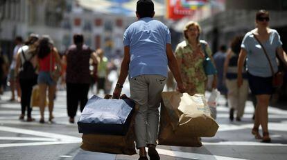Un viandante con varias bolsas de compra (Zara, Springfield, etc) en la calle Preciados de Madrid.