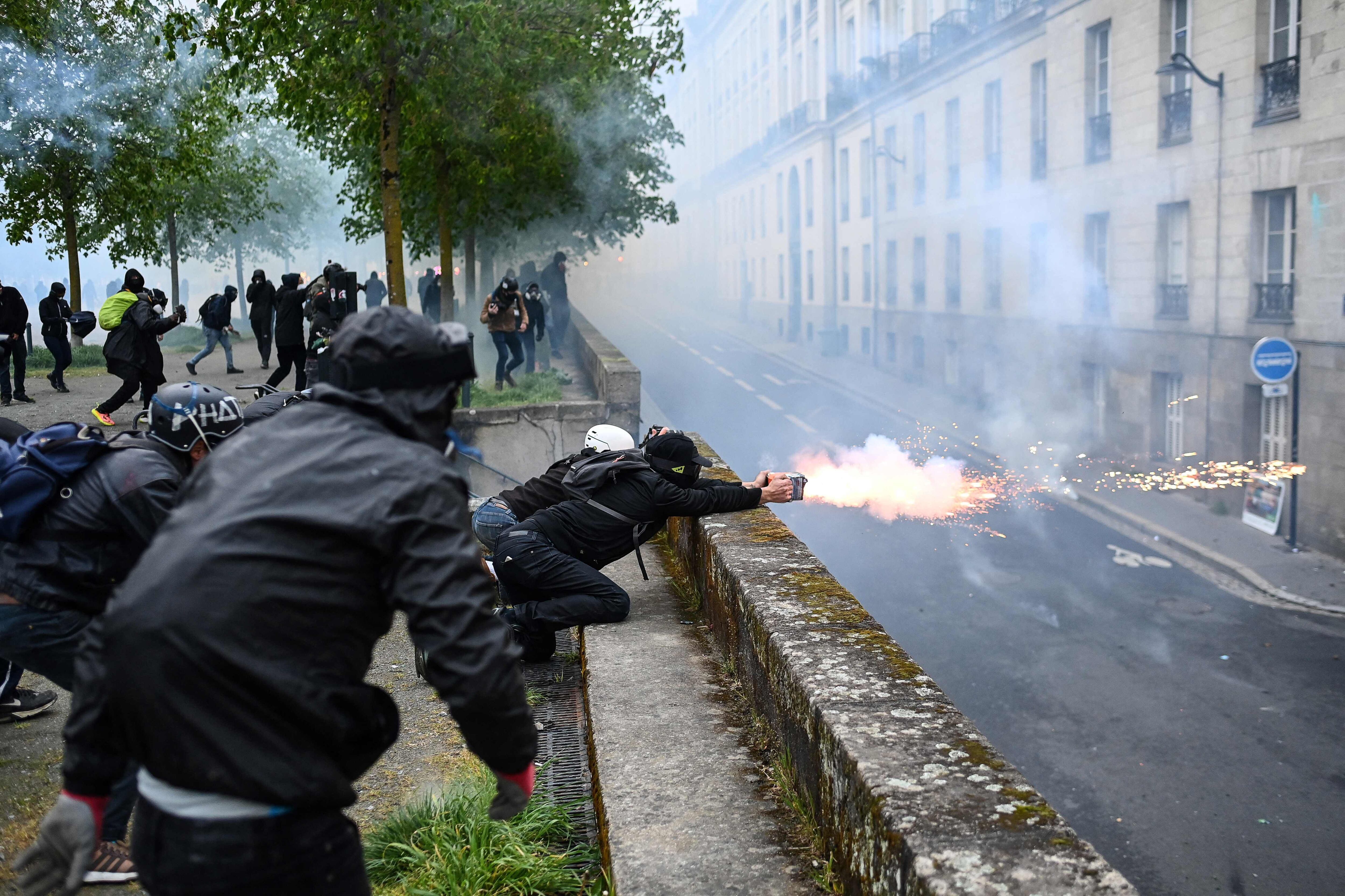 Un manifestante lanza fuegos artificiales durante los enfrentamientos con las fuerzas de seguridad francesas, en París.