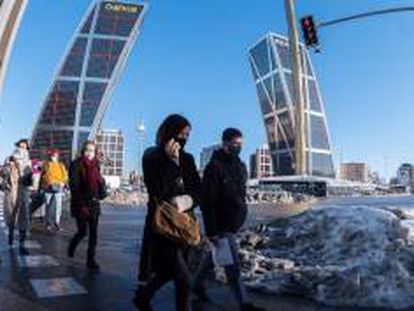 Peatones cruzan una calle en Plaza de Castilla en Madrid, este martes.