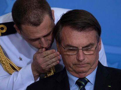 Un militar habla al oído de Bolsonaro en una ceremonia en Brasilia el pasado marzo.