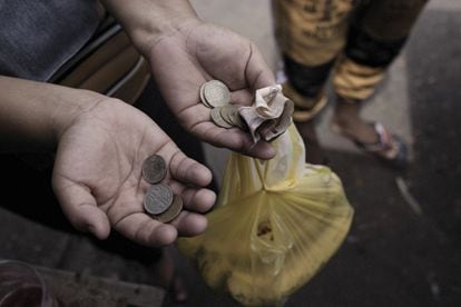 Un cliente sostiene billetes y monedas en un mercado de comida en Riohacha (Colombia).