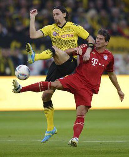Mario Gómez (derecha) protege el balón ante Subotic, del Dortmund, durante un partido de la Bundesliga.