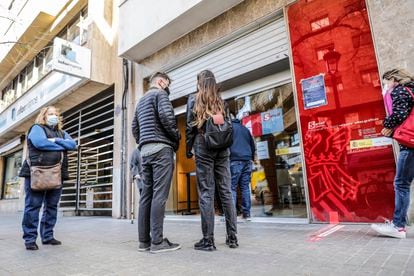 Varias personas hacen cola ante la puerta de oficina de empleo en València.