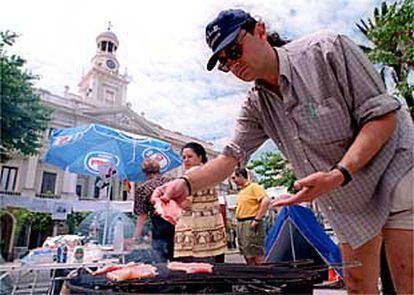 Un trabajador municipal de Cádiz prepara, ayer, una barbacoa en la acampada frente al Consistorio.