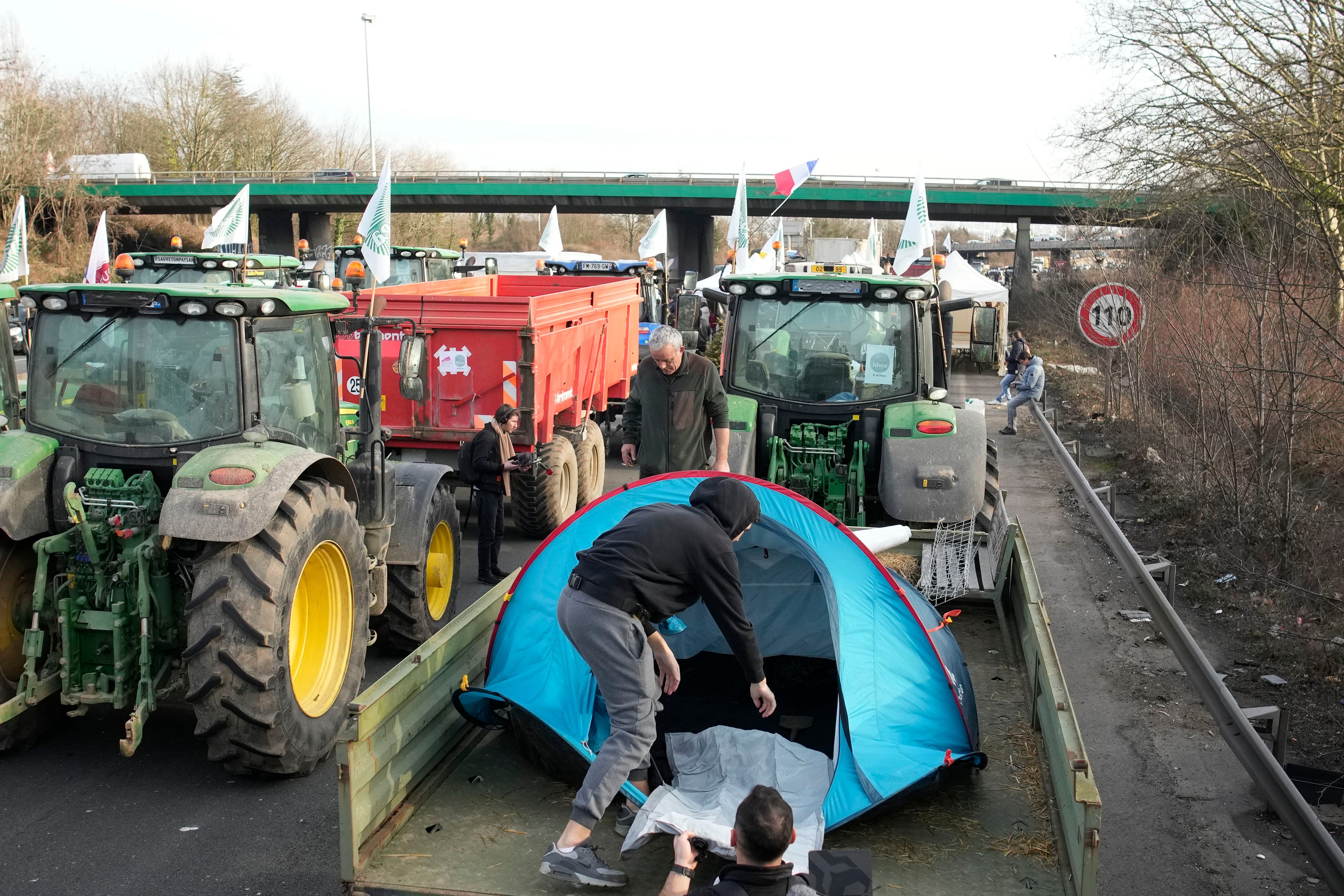 Un agricultor monta una tienda de campaña sobre el remolque de su tractor en una autopista, al norte de París. 