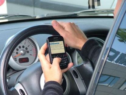 Un conductor utiliza un tel&eacute;fono m&oacute;vil durante la conducci&oacute;n.